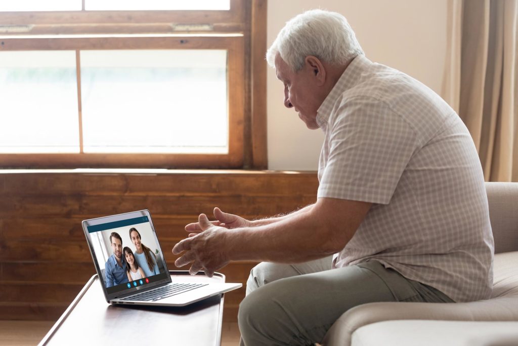 man sitting on couch and watching family over video conference